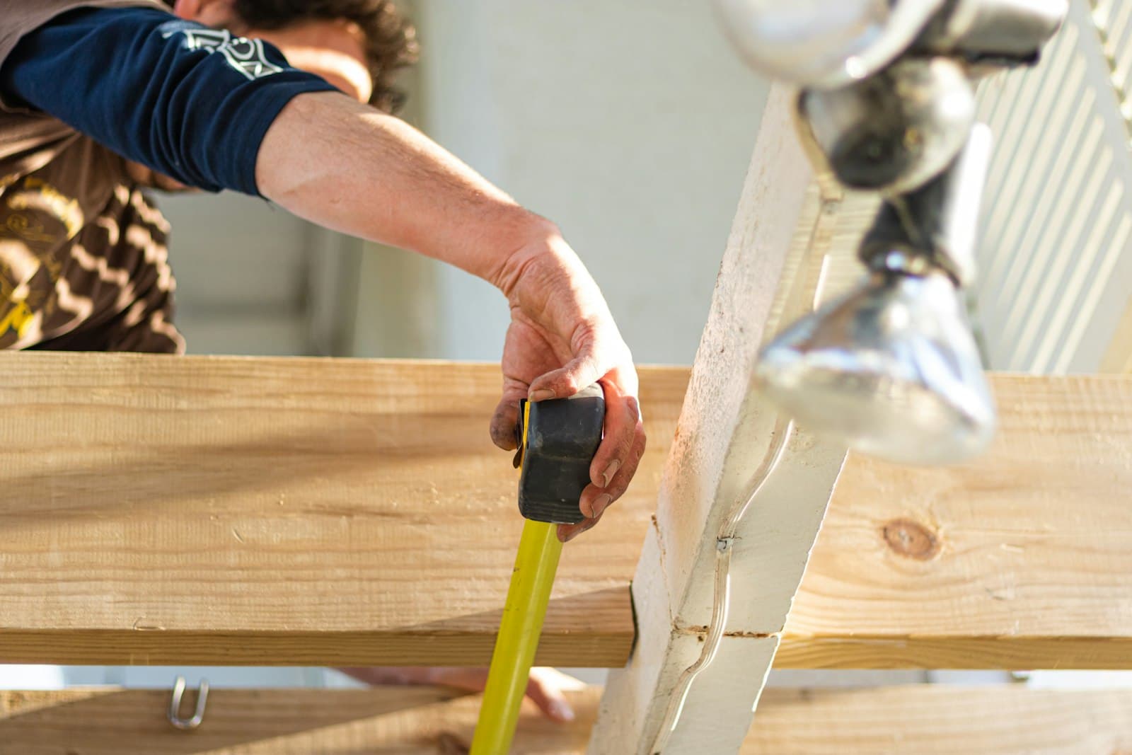 Carpenter measuring lumber with a tape measure before a cut